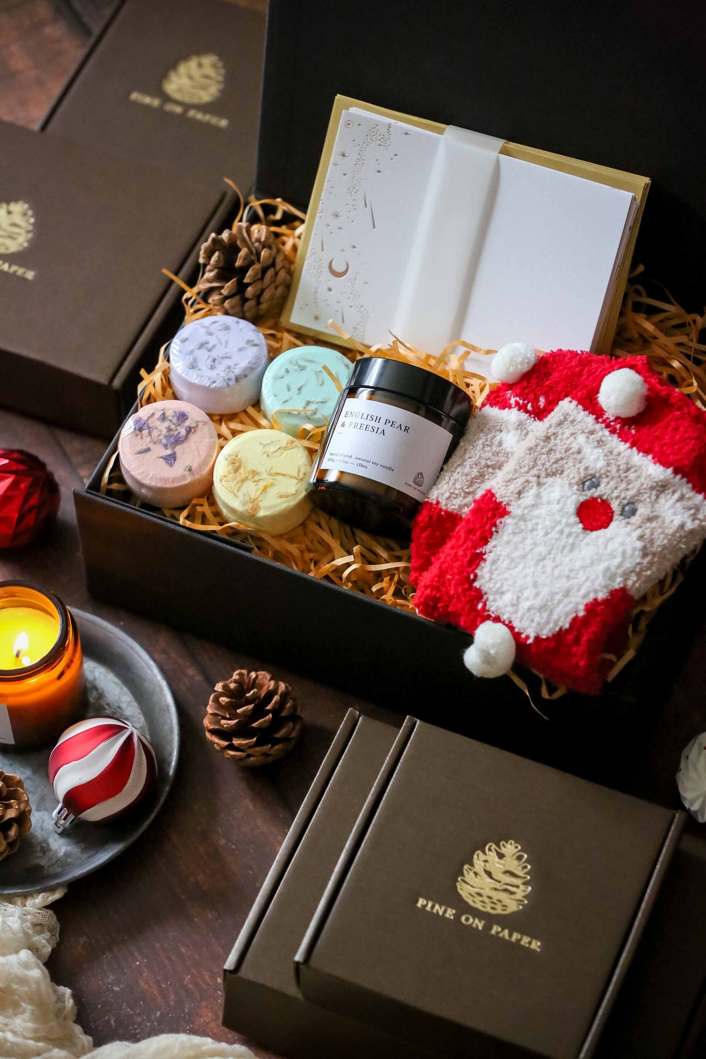 Set includes Box of 10 Foil-Stamped Note Cards, 4 aromatic shower steamers, English Pear & Freesia Soy Wax Candle 100gm, Santa snuggly socks